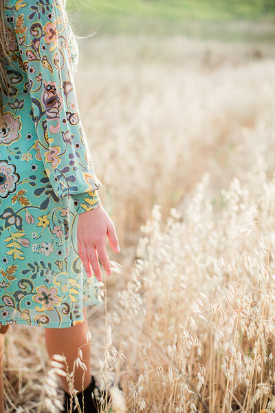 Senior walking in field with focus on her hand