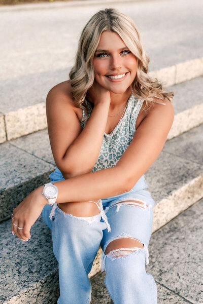 A beautiful Blonde High school Senior is posing on the steps of the Grand Basin for her senior pictures.