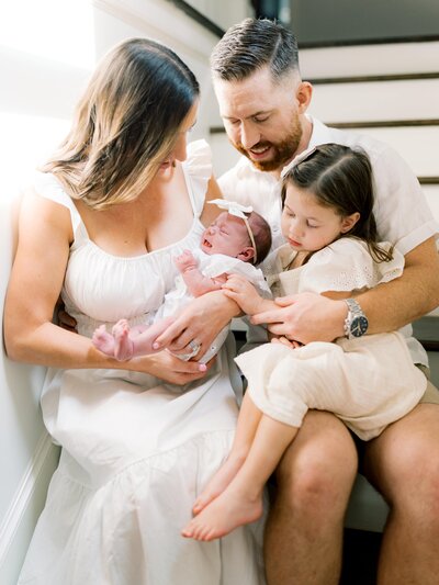 Family portrait on the stairs with young daughter and newborn
