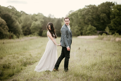 Couple walking in a field in their Arkasnas Engagement Session