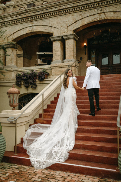 bride and groom holding hands and walking up stairs