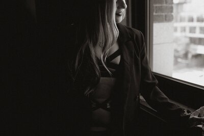 woman in black lingerie looking out of a window