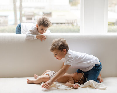 2 young boys crawl around their new baby sister