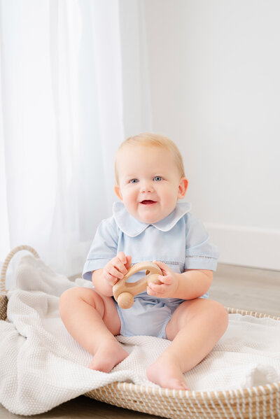 Baby boy smiles with cake during cake smash birthday session.