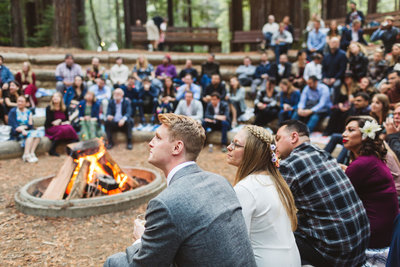 couple enjoying wedding speeches around the campfire at wedding