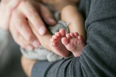 Dad holding newborn showing the baby’stiny feet.