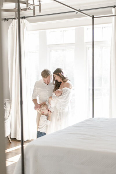 a mother holds her newborn in a luxury master bedroom holding her newborn