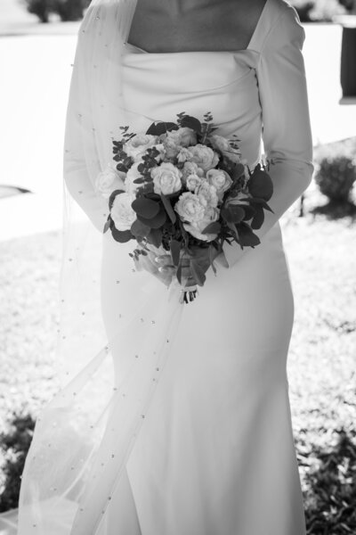 Austin-based wedding photographer captures a captivating black and white photo of a bride gracefully holding her bouquet.