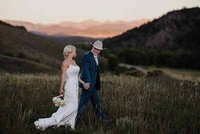 bride and groom walk together during mountain wedding photos.