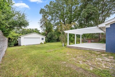 Large backyard with trees, detached garage, and a covered patio perfect for outdoor entertaining.