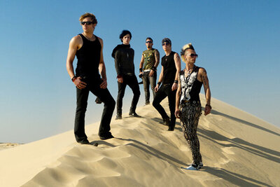 Band portrait My Darkest Days five members standing in V formation on top of sand dune