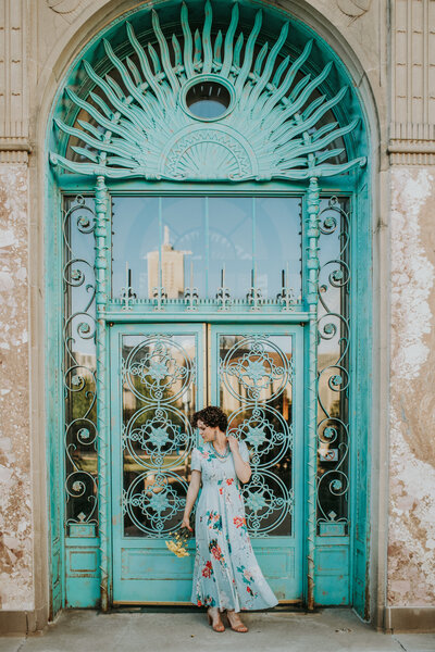 woman wearing dress and standing in front of teal doors