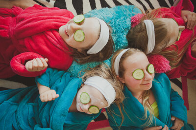 Girls laying together with face masks on and cucumbers on their eyes.