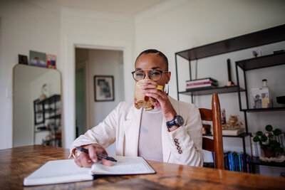 Michaeala Ayers drinking a cup of tea in her office while journaling