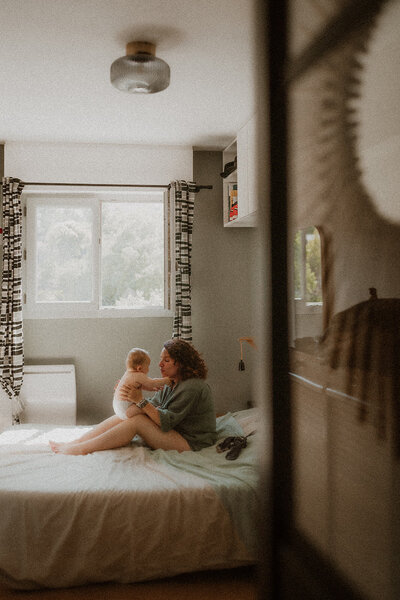 photo bebe sur les genoux de sa maman qui lui parle assis sur le lit