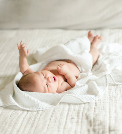 casual newborn baby photography on white bedspread window light