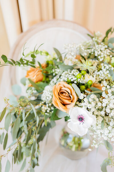 a bridal bouquet with orange and white flowers with greenery