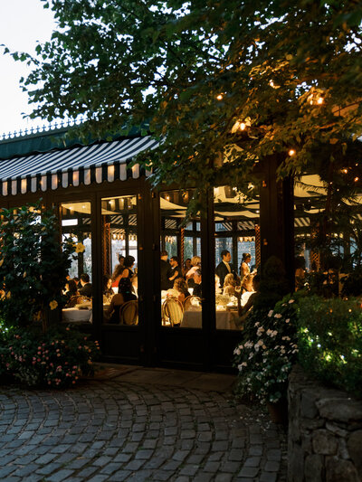 An outdoor view of The River Cafe during an editorial wedding with the guests inside enjoying dinner.