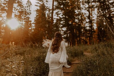 A bride with braided hair at sunrise walking through the forest