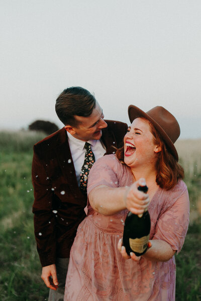 couple smiling while standing in field