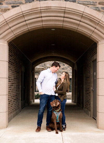 Couple standing under a stone archway with their dog
