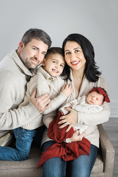 family posing for photos with baby for newborn photography session at studio in Mount Holly, New Jersey.