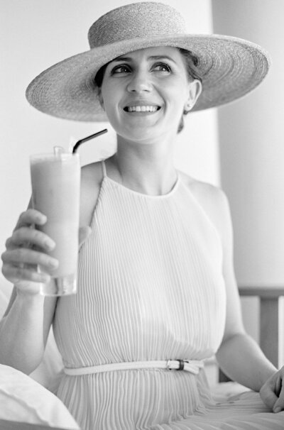 black and white portrait of Emma Wyatt photographer styled in a summer dress and hat with a cocktail