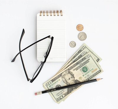 Mockup image of money, glasses and a notepad focusing on budgeting your money