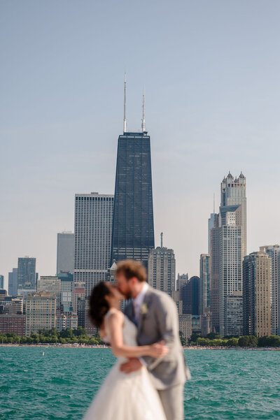 Bride and groom kiss in front of the Chicago Skyline at North Avenue Beach