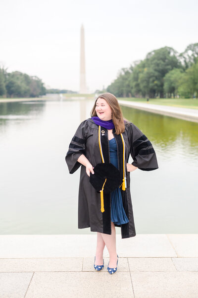 Law school grad smiles while standing on the reflecting pool during DC Graduation Session