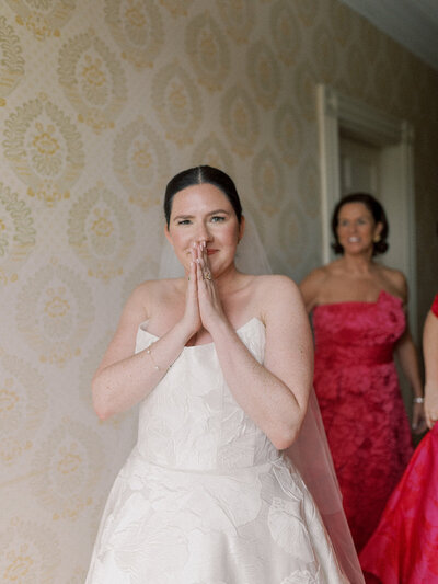 Bride looking at the camera showing excitement with mom looking at her in background