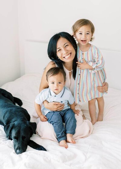 Mai with her two kids smiling with their dog in their home in Zionsville.