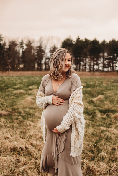 Pregnant woman wearing maternity dress in an open field by Columbus maternity photographer Second Season