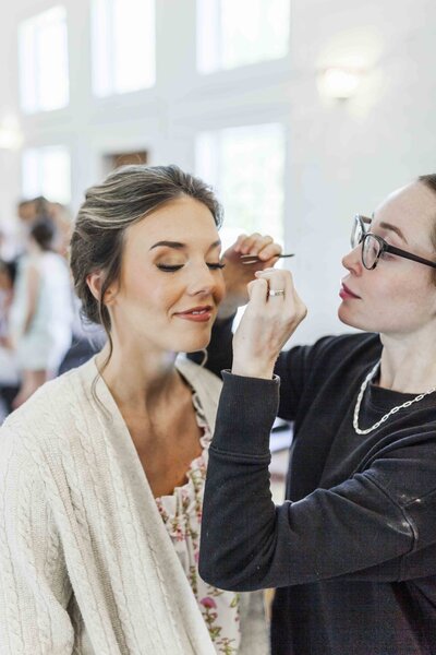 Olivia Sparks applying eyelashes to bride