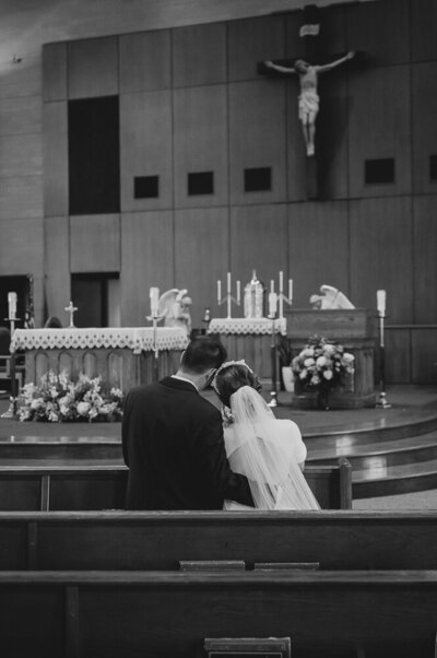 a couple kissing in a Catholic church decorated in a white and peach color scheme