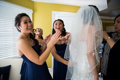Bridesmaids interact with the photographer while the bride is getting ready for her wedding.