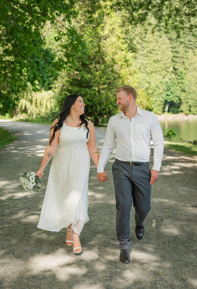 Bride and groom on their wedding look at each other and holding hands.