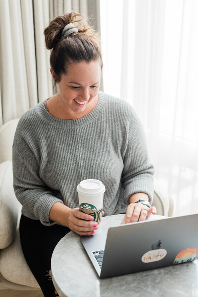 Jess collins working on a laptop holding a coffee