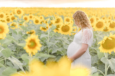 Mum holding baby bump in a Brisbane flower field eagerly waiting for her newborn baby.
