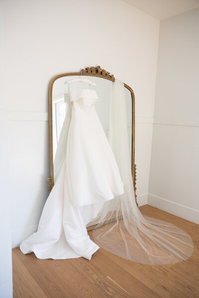 An Austin-based wedding photographer captures a breathtaking image of a wedding dress hanging gracefully in front of a mirror.