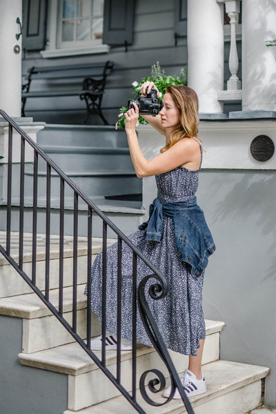 woman standing on stairs taking a picture while wearing a blue dress