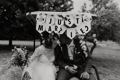 bride and groom kissing under a just married sign
