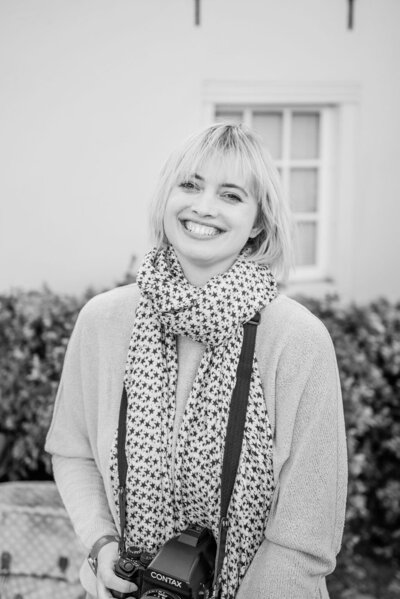 Rosanne van Cruijningen, redacteur en schrijfcoach voor romanschrijvers, kijkt lachend de camera. Op deze foto van vroeger was Rosanne nog werkzaam als fotograaf en journalist. Foto door Wit photography.