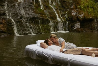 Sweet couple on air mattress in the water in front of a Brasstown Falls, South Carolina.