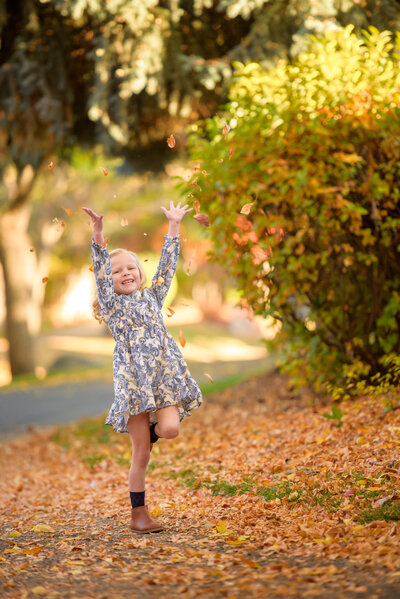 little girl throwing leaves over her head during child pictures with boise photographer tiffany hix