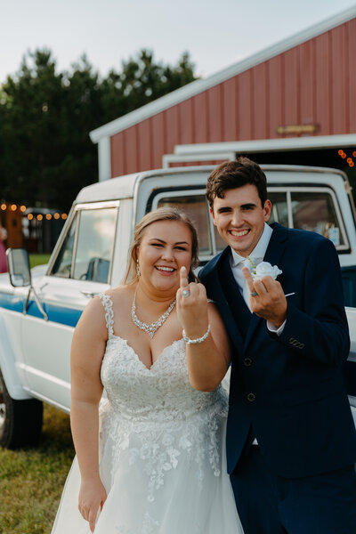 bride and groom flicking off the camera with their ring fingers while laughing