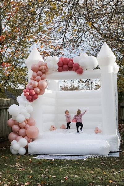 White bounce house inflatable rental with balloon garland for two year old birthday party