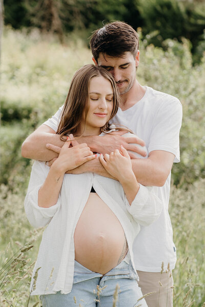 A couple hugging during their pregnancy maternity photoshoot with tashina narelle in auckland