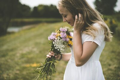 girl smelling a bouquet of colored flowers in a field