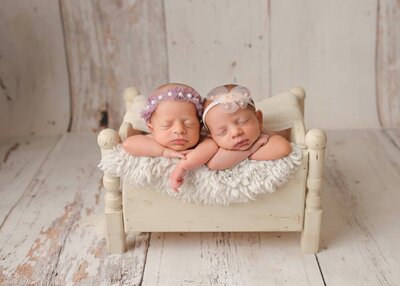 Twin newborns posing side by side in a pretty crate at their denver newborn photography session.